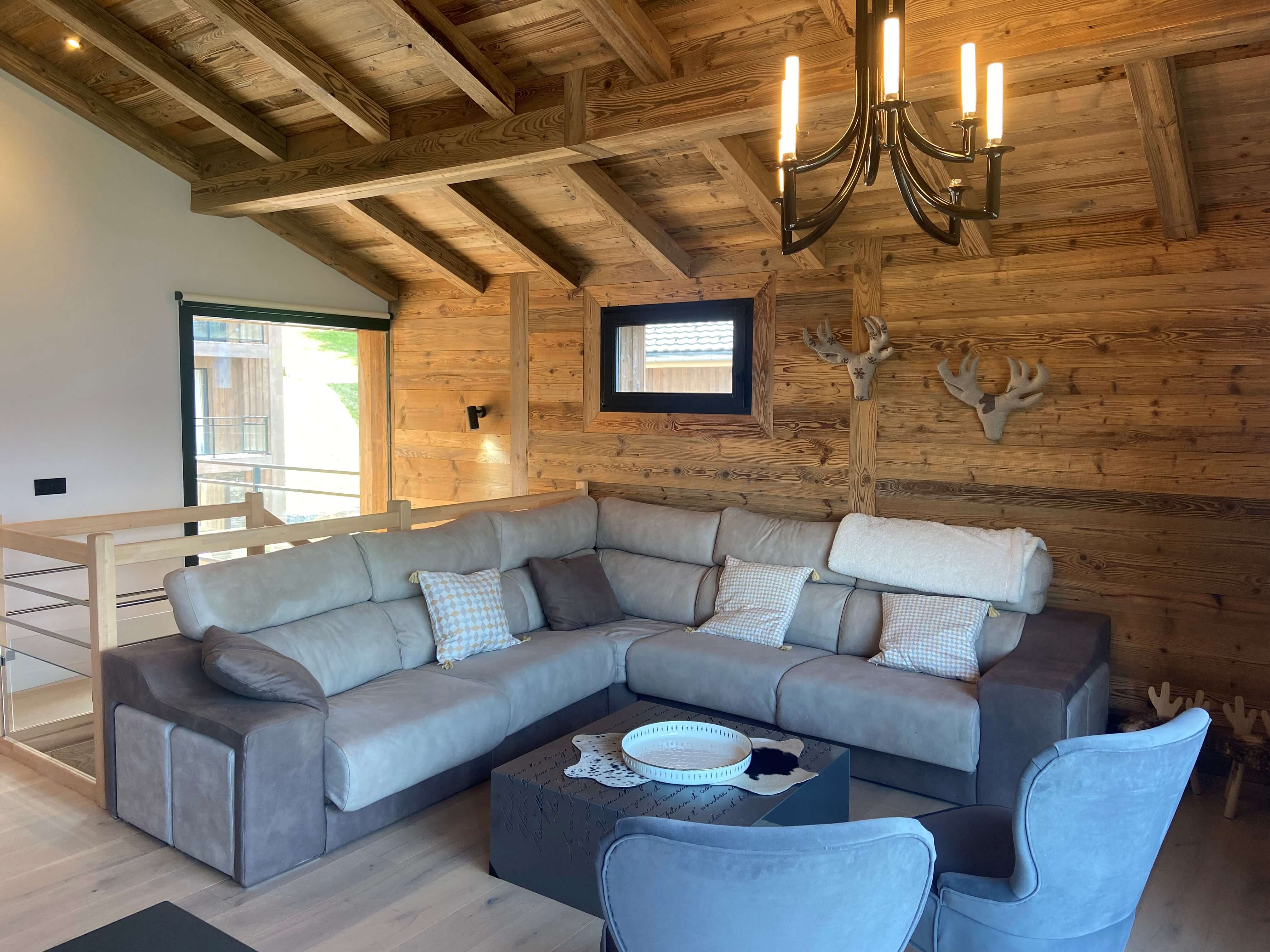 Chalet ASTRO Montalbert - Salon avec canapé et poutres en bois brut